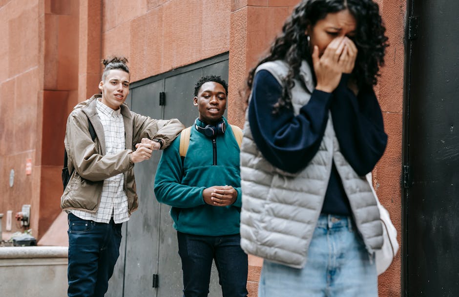 Two individuals, one with a backpack and the other in a green jacket, appear to engage with a distressed woman in a gray vest, highlighting themes of emotional distress and social dynamics related to abusive relationships.